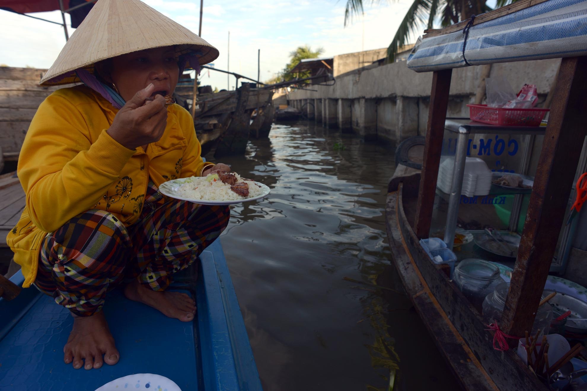 Một cô chạy chợ dừng xuông ăn vội đĩa cơm cho chắc dạ trước khi khua chèo rảo chợ mua bán. 
