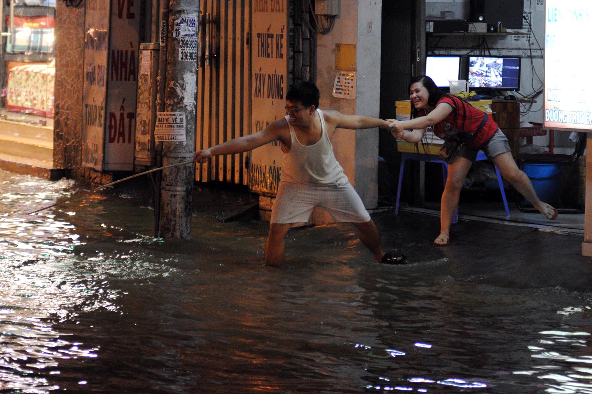 Một đôi bạn cố gắng lấy lại chiếc dép bị dòng nước cuốn đi trên đường Huỳnh Tấn Phát, quận 7.