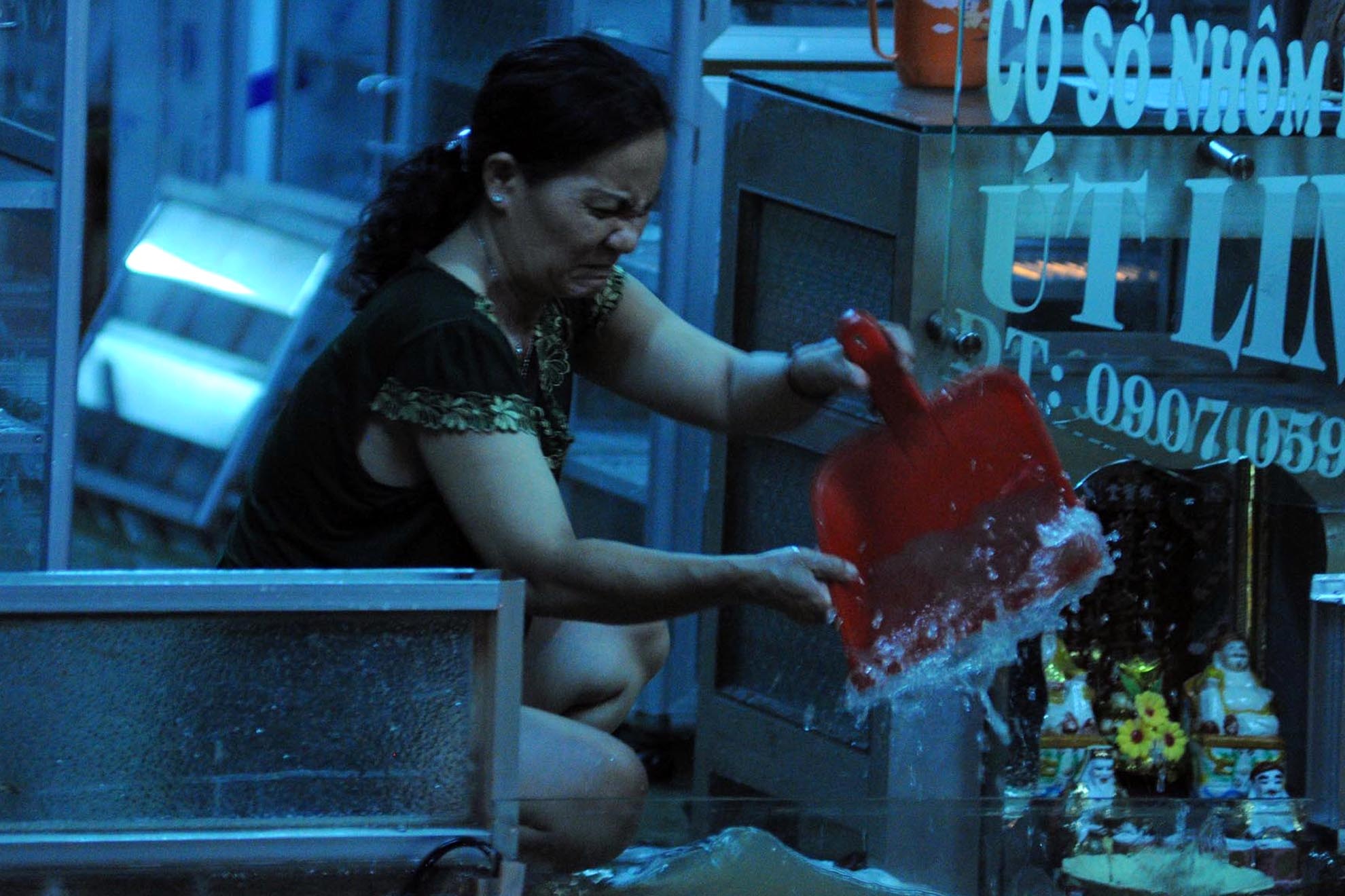 Người dân cố gắng tát nước ra khỏi nhà trong sự bất lực, chán nản.