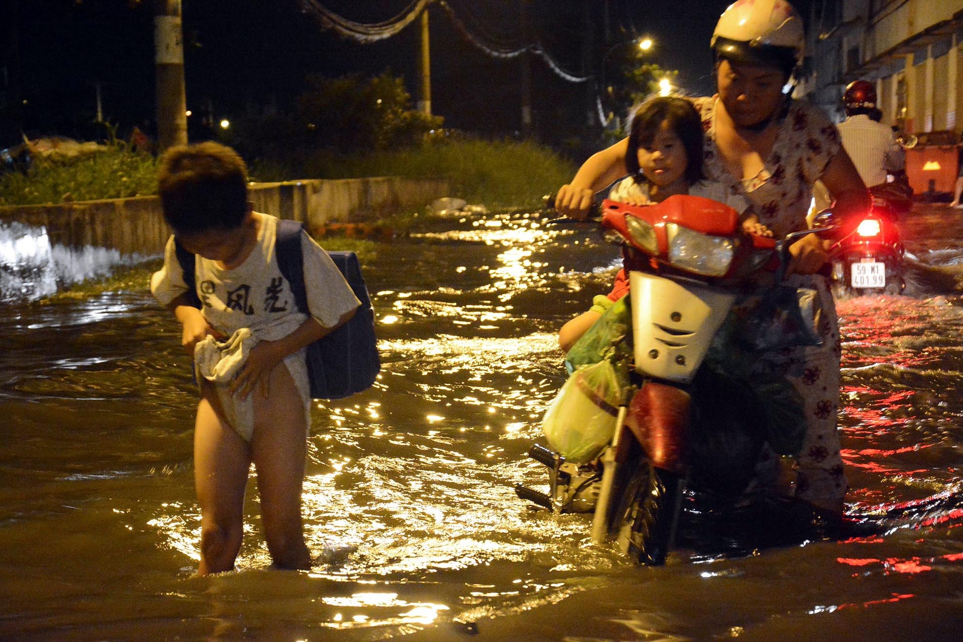 Một cậu bé tan trường về phải vén cao quần lội bì bõm trên tuyến đường Bến Phú Định, quận 8.