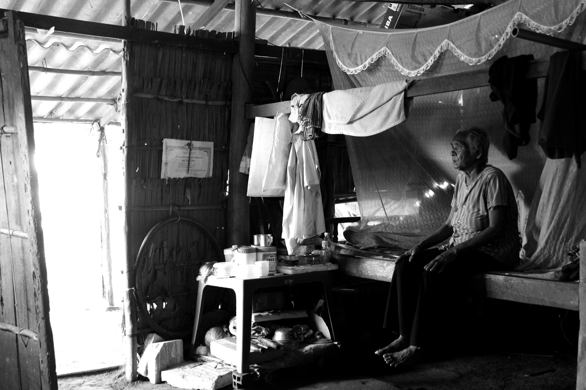 Cụ Kim Thị Hiêm cũng bị hỏng một mắt sau nhiều năm làm hành, hiện nay cụ sống trong một căn nhà lá dột nát chỉ chờ sập. Trong nhà không có thứ gì đang giá. Cụ quá già, yếu để lao động.