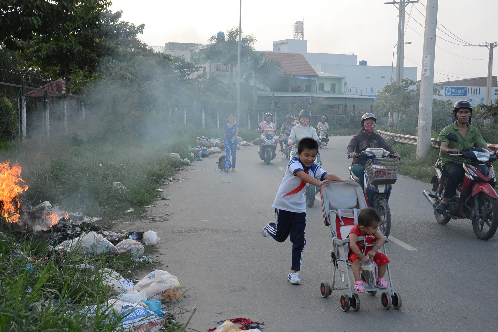 Cậu bé đẩy xe đưa em thoát khỏi đám khói độc một cách nhanh chóng. Con đường này là nơi đi về thường xuyên của nhiều học sinh các cấp.