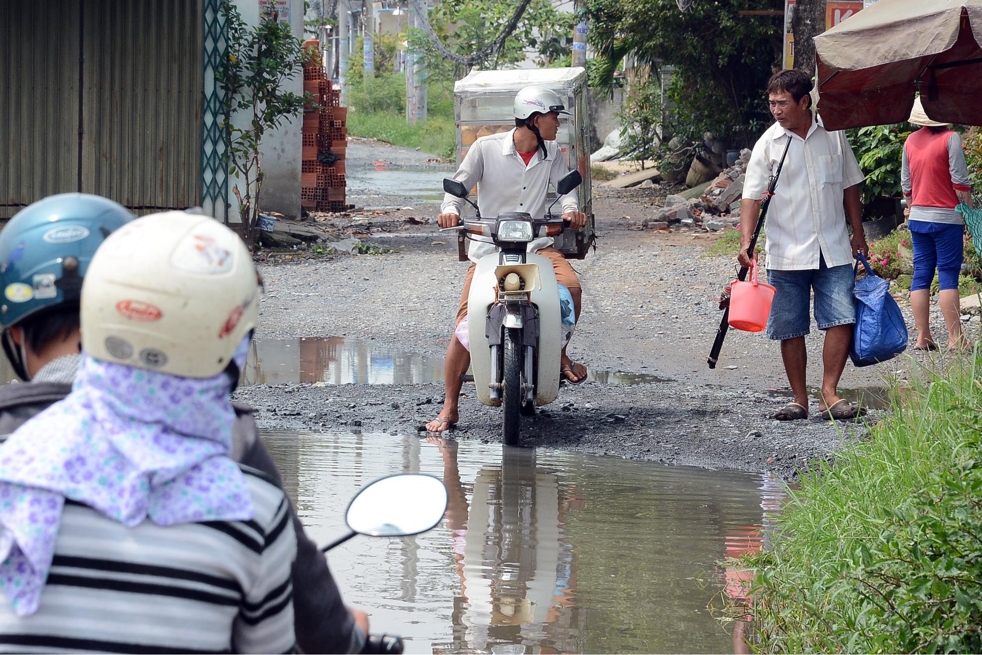 Một người đàn ông dò hỏi người dân, trước khi đi qua vũng nước này. 