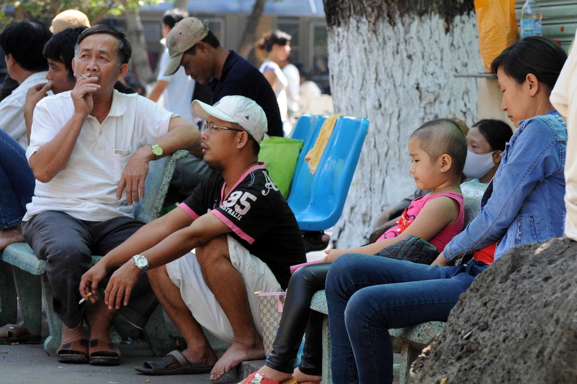 Hai người đàn ông vô tư hút thuốc bên cạnh một em bé ở bệnh viện.