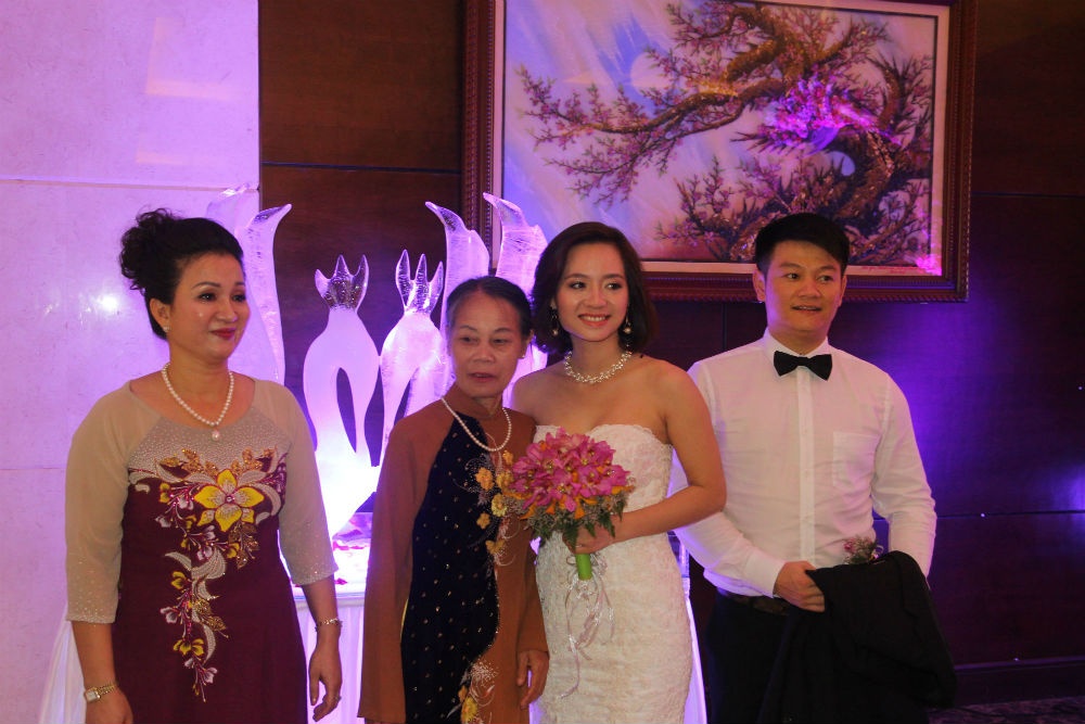 Hai bà thông gia chụp ảnh cùng cô dâu, chú rể.