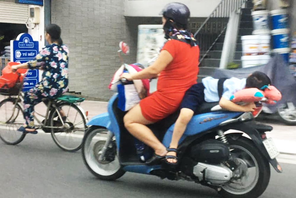Nguoi phu nu buoc dua tre sau xe may o TP.HCM hinh anh