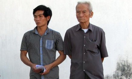Ông Truyện (bên phải) và con của bị can Huỳnh Văn Nén lặng người khi nhận thư trả lời không chấp nhận cho tại ngoại của cơ quan điều tra.
