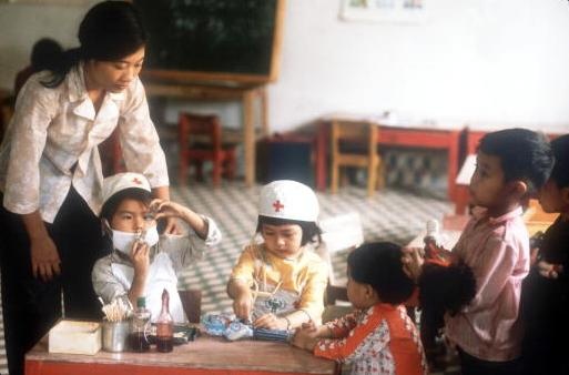 Cô giáo quan sát các em bé chơi trò đóng giả bác sĩ và bệnh nhân tại một trường học ở Vinh.
