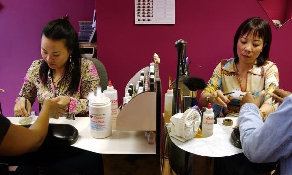 Hai phụ nữ gốc Việt đang chăm sóc móng cho khách hàng. Ảnh: AFP