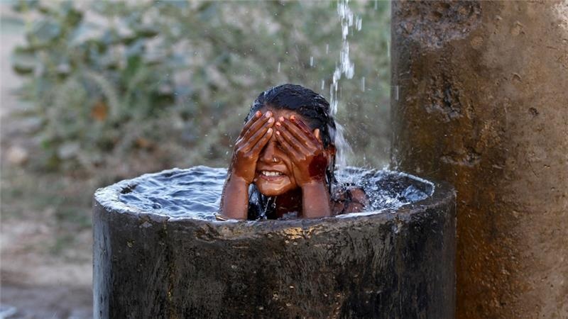 Một cô bé ngồi trong chum nước để tắm tại thành phố Ahmedabad. Chính phủ khuyến cáo người dân không nên ra đường để tránh ảnh hưởng sức khỏe. Phần lớn những người thiệt mạng là người vô gia cư. Ảnh: Reuters