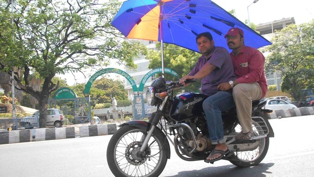 Người đàn ông phải gắn dù lên xe máy để che nắng khi đi ngoài đường. Giới chức Ấn Độ cho biết, khoảng 230 người ở các bang miền nam đã thiệt mạng trong mùa hè nóng bức bắt đầu từ giữa tháng 4. Ảnh: Indian Express