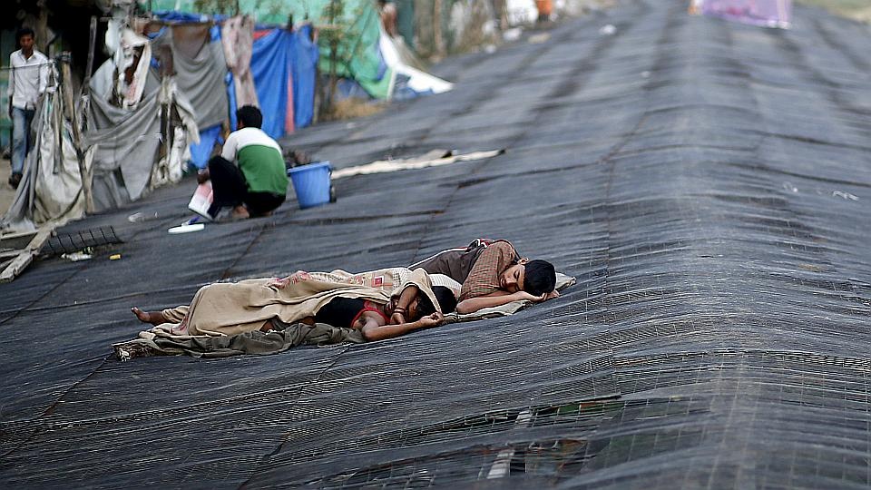 Người dân Ấn Độ ngủ dưới bóng râm của một tòa nhà. Andhra Pradesh và Telangana là hai bang có số người chết cao nhất cả nước: 1979 ca tử vong. Chỉ trong ngày 29/5, 156 người ở Andhra Pradesh và 49 người Telangana đã thiệt mạng vì trời nắng nóng.