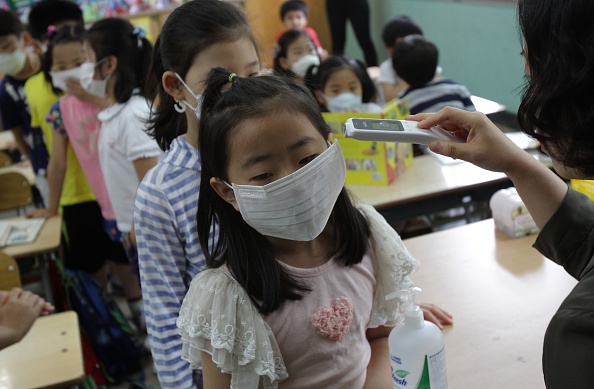 Giáo viên tại trường tiểu học Midlong kiểm tra nhiệt độ của học sinh. 