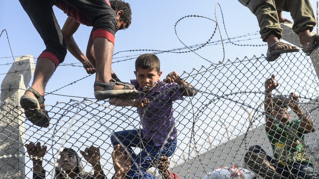 Một cậu bé trèo qua hàng rào để đến các trại tị nạn của người Syria bên trong Thổ Nhĩ Kỳ. Ảnh: AFP