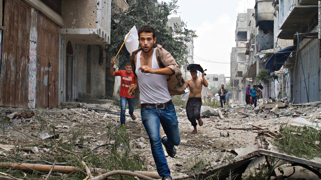 Người Palestine chạy trốn tên lửa của Israel, tay cầm cờ trắng tự tạo để ra dấu hiệu. 