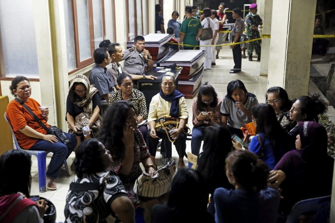 Thân nhân người bị nạn ngồi chờ đợi tin tức người nhà bên ngoài bệnh viện Adam Malik. Ảnh: Reuters