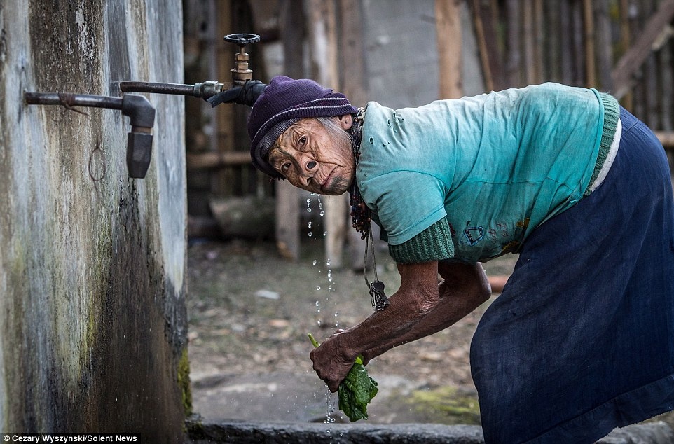 Một cụ bà rửa rau bên giếng nước trong nhà. Ngành sản xuất chính của người dân nơi đây là nông nghiệp.