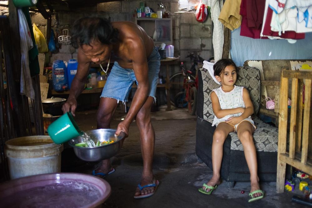 Bé Francine (7 tuổi) ngồi trên ghế trong khi ông ngoại của em đang rửa rau. Bố của em vốn là du khách người Australia. Cô bé chưa từng được gặp bố.