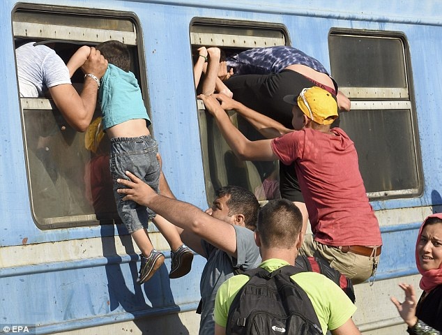 Một người đàn ông giúp cậu bé lên tàu qua đường cửa sổ, trong khi bố của em nắm lấy cánh tay con để kéo vào bên trong toa.