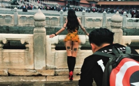Cô gái khỏa thân tựa vào lan can trước cửa điện chính. Phía xa là rất đông du khách tham quan.