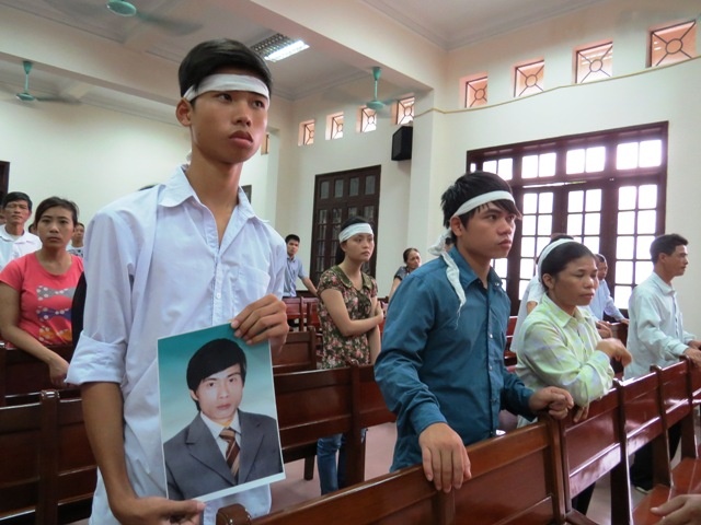 Người nhà nạn nhân khăn trắng đầu, mang theo di ảnh của anh Hóa đến dự tòa. Giang Chinh.