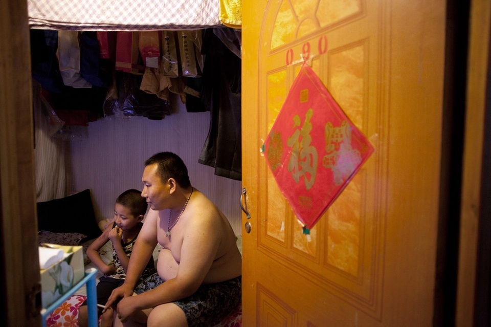 Anh Sun Kuangda, 29 tuổi, và con trai Xiang Song 8 tuổi đang xem truyền hình tại căn phòng trọ dưới một tầng hầm ở phía tây Bắc Kinh. Những người không đủ tiền thuê phòng trọ trên mặt đất mà phải tìm đến những căn phòng dưới tầng hầm thường là nhân viên bồi bàn, tiếp viên karaoke, thợ cắt tóc, đầu bếp, bảo vệ, công nhân, người giúp việc... Vào mùa hè, các căn phòng trở nên ẩm ướt và mốc meo.