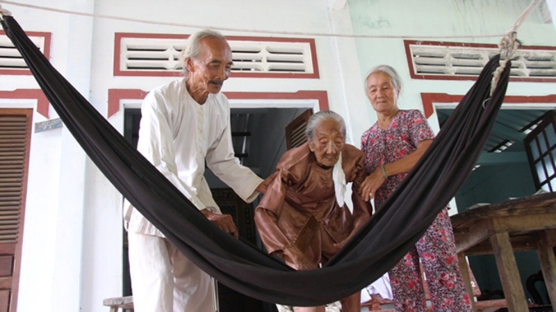 Cứ đến 11g trưa là ông Đức có mặt bên mẹ già để cho cụ ăn. Còn bà Trừ luôn bên cạnh để quạt và cho cụ uống nước. Lo cho mẹ xong, ông Đức ăn trưa rồi đạp xe  ra ruộng cách nhà chừng hơn 1km chăm sóc lúa đến chiều.